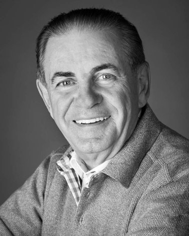 Portrait en plan rapproché de M. Jacques Duchesneau, réalisé en studio photo noir et blanc, homme souriant décontracté