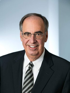 Portrait corporatif d'un dirigeant  d'un cabinet d'avocats, photo couleur, fond neutre, le sujet porte complet cravate et est souriant
