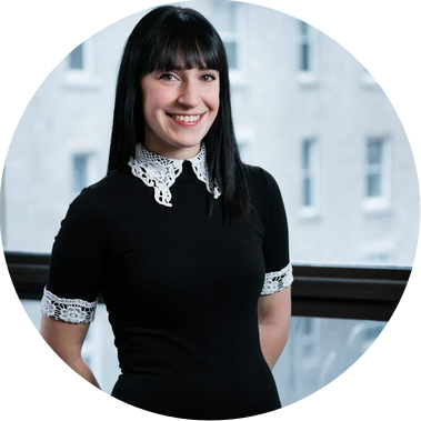 Portrait corporatif d'une employée d'un bureau d'architectes photographiée devant la fenêtre, souriante, les bras derrière le dos
