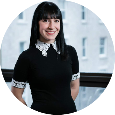 Portrait corporatif d'une employée d'un bureau d'architectes photographiée devant la fenêtre, souriante, les bras derrière le dos