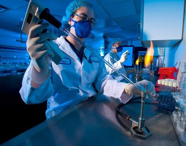 Photo industrielle dans un laboratoire de recherche technicien  au premier plan, fioles  éprouvettes