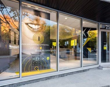 Façade d'une boutique Vidéotron rue Beaubien à Montréal grande affiche montrant un sourire et paysage automnal en réflexion