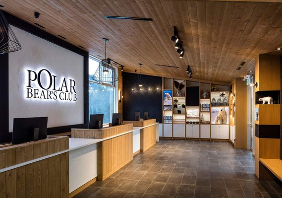 Réception du Polar Bear's Club avec ses comptoirs, ordinateurs,son grand logo au mur et des présentoirs avec souvenirs à vendre