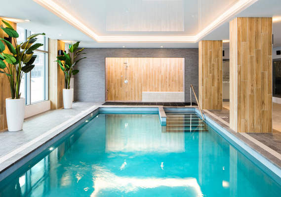 Piscine dans une résidence pour personnes âgées, montrant l'eau turquoise, les murs de bois  et les planchers de céramique