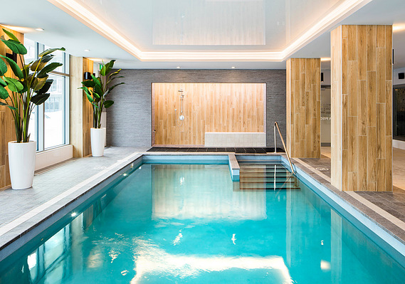 Piscine dans une résidence pour personnes âgées, montrant l'eau turquoise, les murs de bois  et les planchers de céramique