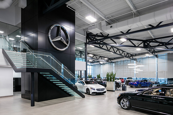 Photo d'architecture intérieure du concessionnaire automobile Mercedes-Benz Rive-Sud, mettant en vedette un grand escalier menant à l'étage, sous une grand logo de la prestigieuse marque
