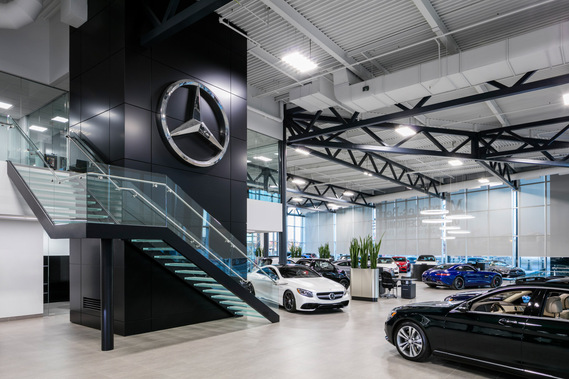 Photo d'architecture intérieure du concessionnaire automobile Mercedes-Benz Rive-Sud, mettant en vedette un grand escalier menant à l'étage, sous une grand logo de la prestigieuse marque