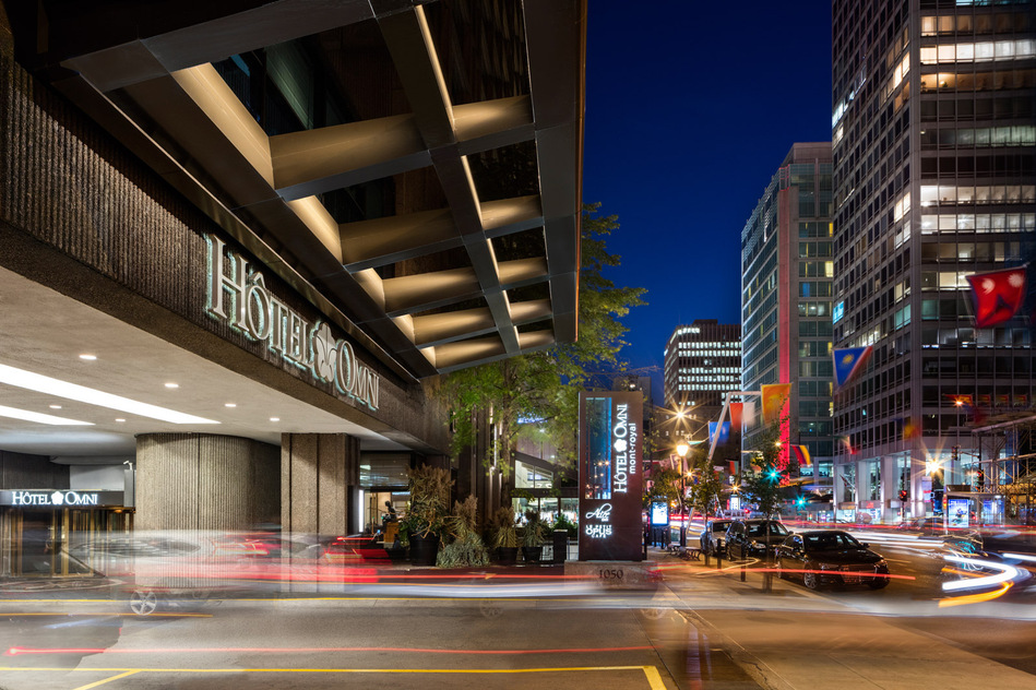 Entrée de l'hôtel Omni, rue Sherbrooke à Montréal, montrant son entrée principale, le logo sur la façade, et la circulation automobile intense du centre-ville
