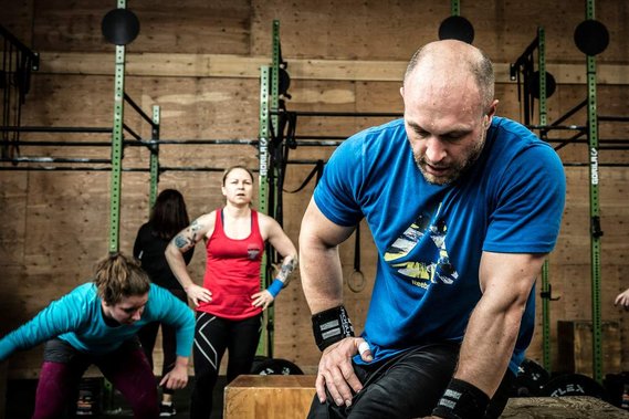 Photo de gens en action à un cours de CrossFit, homme essoufflé, au repos après un effort intense