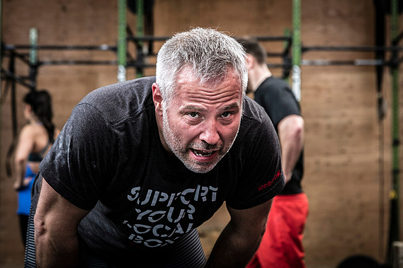 Homme accroupi tenete de reprendre son souffle après un exercice exigent lors d'une session de crossfit