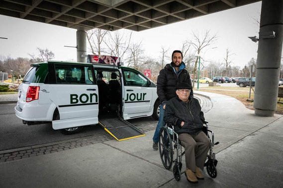 Service d'accompagnement à l'hôpital offert par COOP Taxi, un chauffeur emmène un patient en fauteuil rouant vers l'entrée de l'hôpital