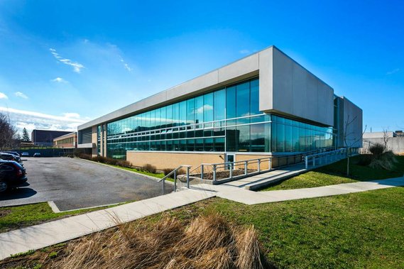 Photo architecturale d'une école située à Montréal, montrant ses grandes fenêtres, le stationnement et l'aménagement paysager
