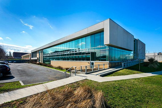 Photo architecturale d'une école située à Montréal, montrant ses grandes fenêtres, le stationnement et l'aménagement paysager