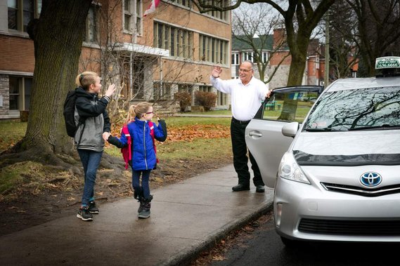 Service d'accompagnement à l'école offert par COOP Taxi deux enfants saluent le chauffeur qui vient de les déposer à l'école