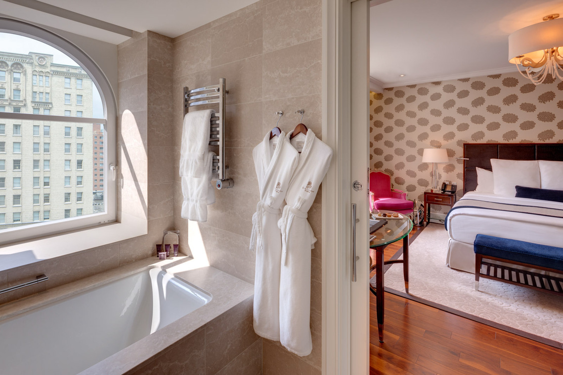 Chambre de l'hôtel Ritz-Carlton à Montréal montrant la salle de bain, un peignoir accroché au mur et une grand lit dans la chambre adjacente