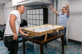 Employés jouant au baby foot dans un bureau d'une entreprise  de technologies de l'information, l'un d'eux a les bras dans les airs en signe de victoire