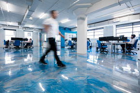 Employé qui travers flou un espace à bureaux, le plancher de béton peint en bleu, de vastes espaces de bureaux visibles à l'arrière plan
