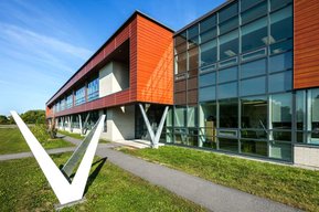 Photo architecturale extérieure d'une école montrant sa fenestration généreuse et l'utilisation du bois pour ses recouvrements extérieurs