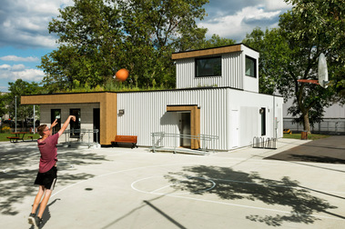 Photo d'architecture extérieur de l'aménagement du parc Stewart, montrant un jeune homme jouant au basketball, devant in pavillon aménagé à l'arrière plan