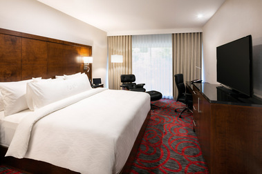 Photo architecturale d'une chambre de l'hôtel OTL à Sherbrooke montrant un grand lit king au premier plan ainsi que la télé et un petit bureau à l'arrière plan