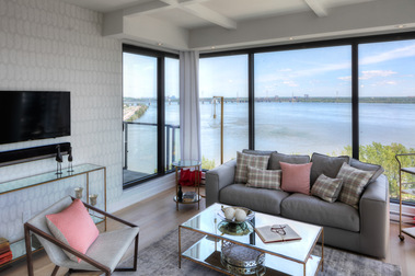 Salon dans un condo à l'Ile des Soeurs à Montréal, divan avec plusieurs coussin, tables à café, télé accrochée au mur