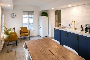Cuisine aménagée pour les employés d'une clinique médicale, grande table de bois, long comptoir en marbre blanc, espace salon confortable, belle luminosité