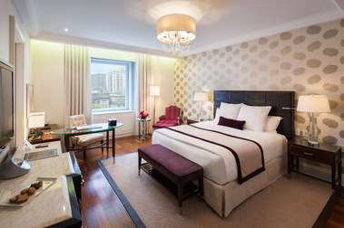 Chambre de l'hôtel Ritz-Carlton à Montréal avec son grand lit, un petit bureau à l'arrière plan et des chocolats déposés sur la commode à l'entrée