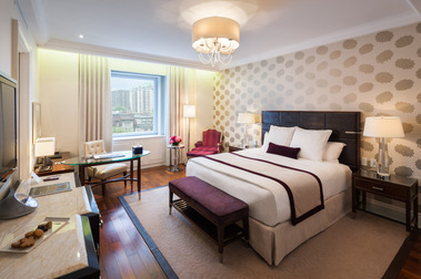 Chambre de l'hôtel Ritz-Carlton à Montréal avec son grand lit, un petit bureau à l'arrière plan et des chocolats déposés sur la commode à l'entrée