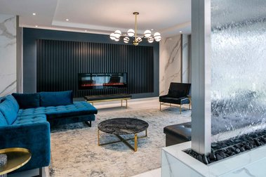 Hall d'entrée du complexe de condos Marquise Phase III, à Laval, fauteuils en velours bleu foncé, foyer, mur de cascades d'eau