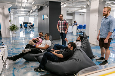 Employés en action ou en pause dans un bureau d'une entreprise  de technologies de l'information, assis confortablement sur de grands coussins, jouant à des jeux vidéos