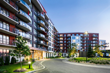 Résidence pour personnes âgées Terrebonne, prise au crépuscule, montrant le façade, les nombreux balcons, son entrée principale, avec plantes et végétation décorative