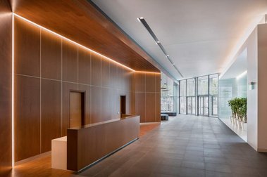 Vue du hall d'entrée d'un édifice à bureaux au 1100 Atwater à Montréal, montrant le bureau de la réception, des plantes vertes et de grandes vitrines
