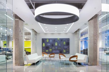 Hall d'entrée d'un grand magasin d'ameublement de bureau avec chaises et divans sous un immense luminaire circulaire