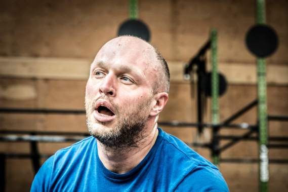 Homme reprenant son souffle, bouche ouverte dans un cours de Crossfit