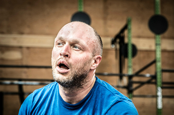 Homme reprenant son souffle, bouche ouverte dans un cours de Crossfit