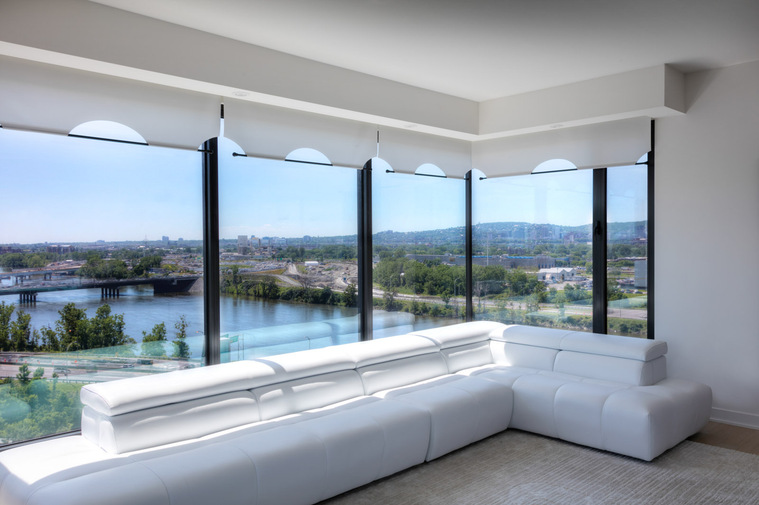 Photo d'architecture intérieure d'un condo à l'Ile des Soeurs à Montréal, montrant un grand canapé et la vue du centre-ville à l'arrière plan