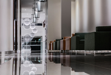 Corridor de l'hôtel OTL à Sherbrooke, photographié au niveau du sol où on voit en réflexion les luminaires du lobby et des fauteuils sur le côté de la photo