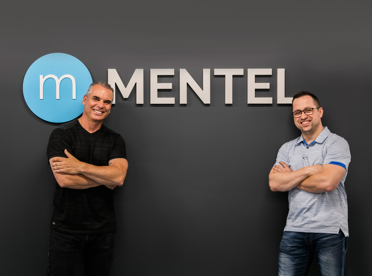 Portait corporatif de deux dirigeants d'une entreprise de technologies de l'information, posant tous deux bras croisés de part et d'autre du logo de la compagnie