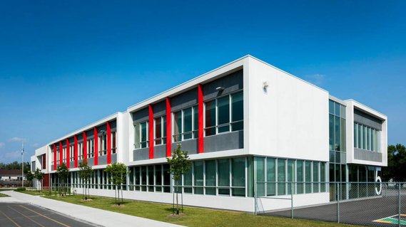 École photographiée en plein soleil grandes fenêtres et colonnes rouges