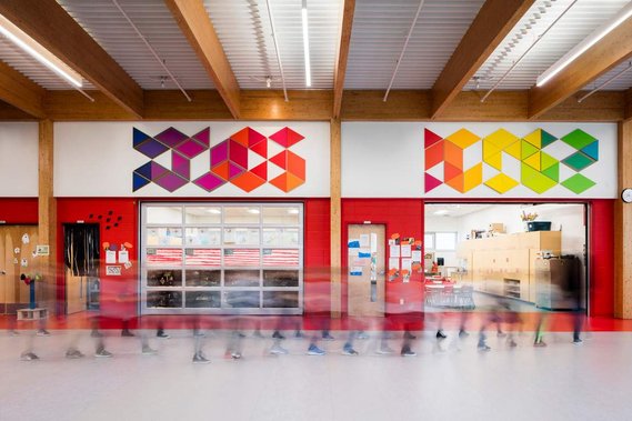 Photo d'architecture intérieure d'un école montrant un espace commun où défilent des enfants en mouvement