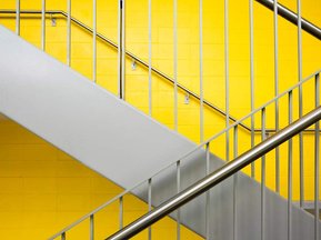 Photo  d'un escalier dans une école de Montréal vu de profil rampes en acier et murs jaunes