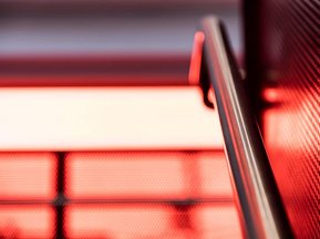 Escalier dans une école de Montréal dont on voir une rampe en acier au premier plan et des fenêtres flous à l'arrière