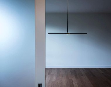 Photo abstraite montrans une portr coulssante devant une salle à manger vide et un luminaire suspendu au plafond