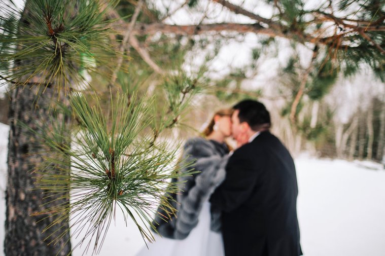 A couple kissing in the foreground, surrounded by snow