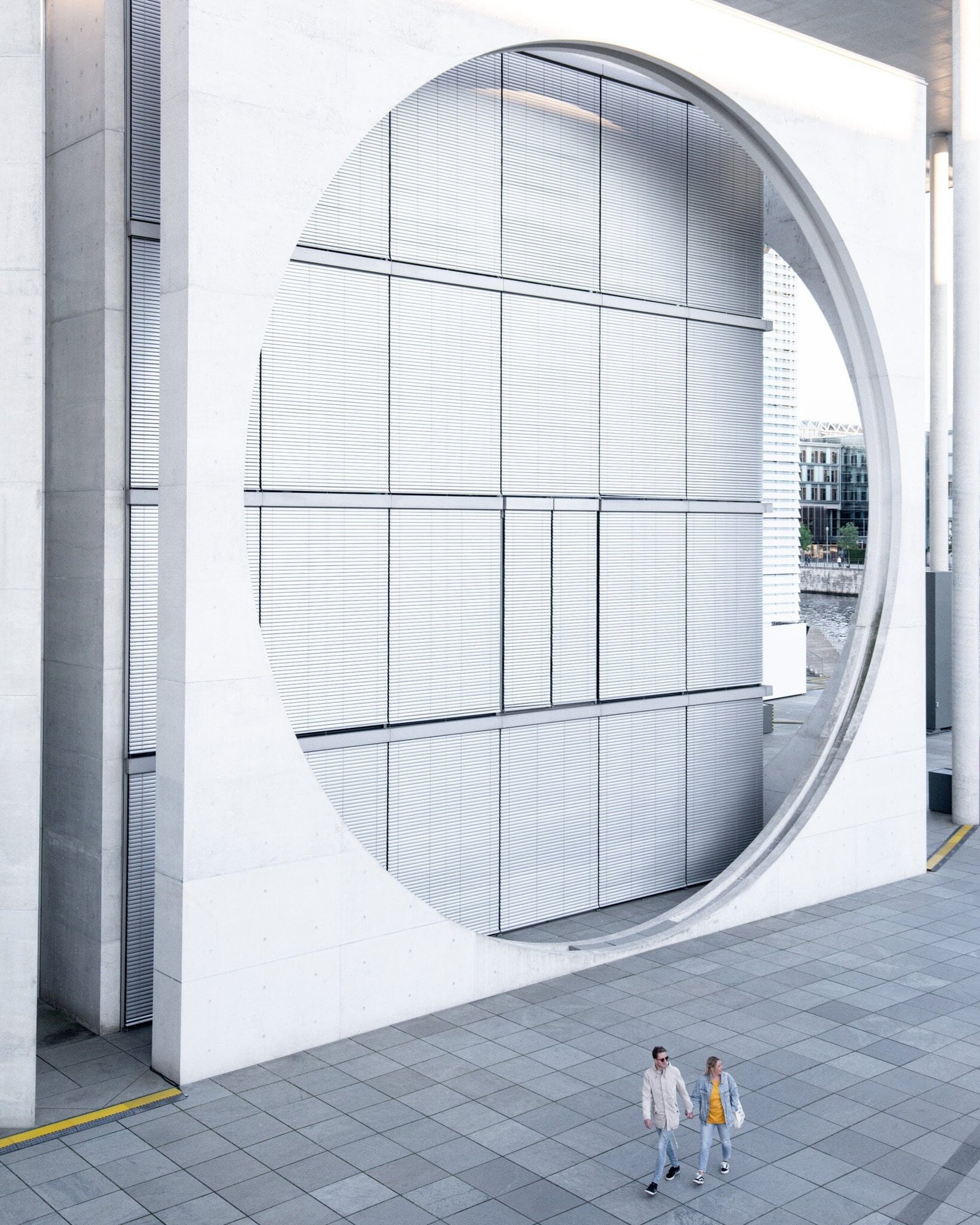 Architecture photography showing couple walking in front of modern building with a round cut out