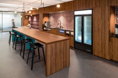 Interior photography of a contemporary office kitchenette with subway tile backsplash, polished concrete counters, and communal dining space
