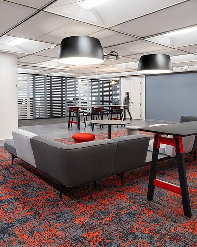 High-quality interior shot of a workplace breakout area with colorful modular seating, and flexible layouts designed for team interaction.