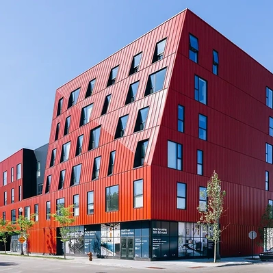 Exterior architecture photography featuring a modern red-colored apartment building, showcasing its contemporary design and vibrant color scheme.