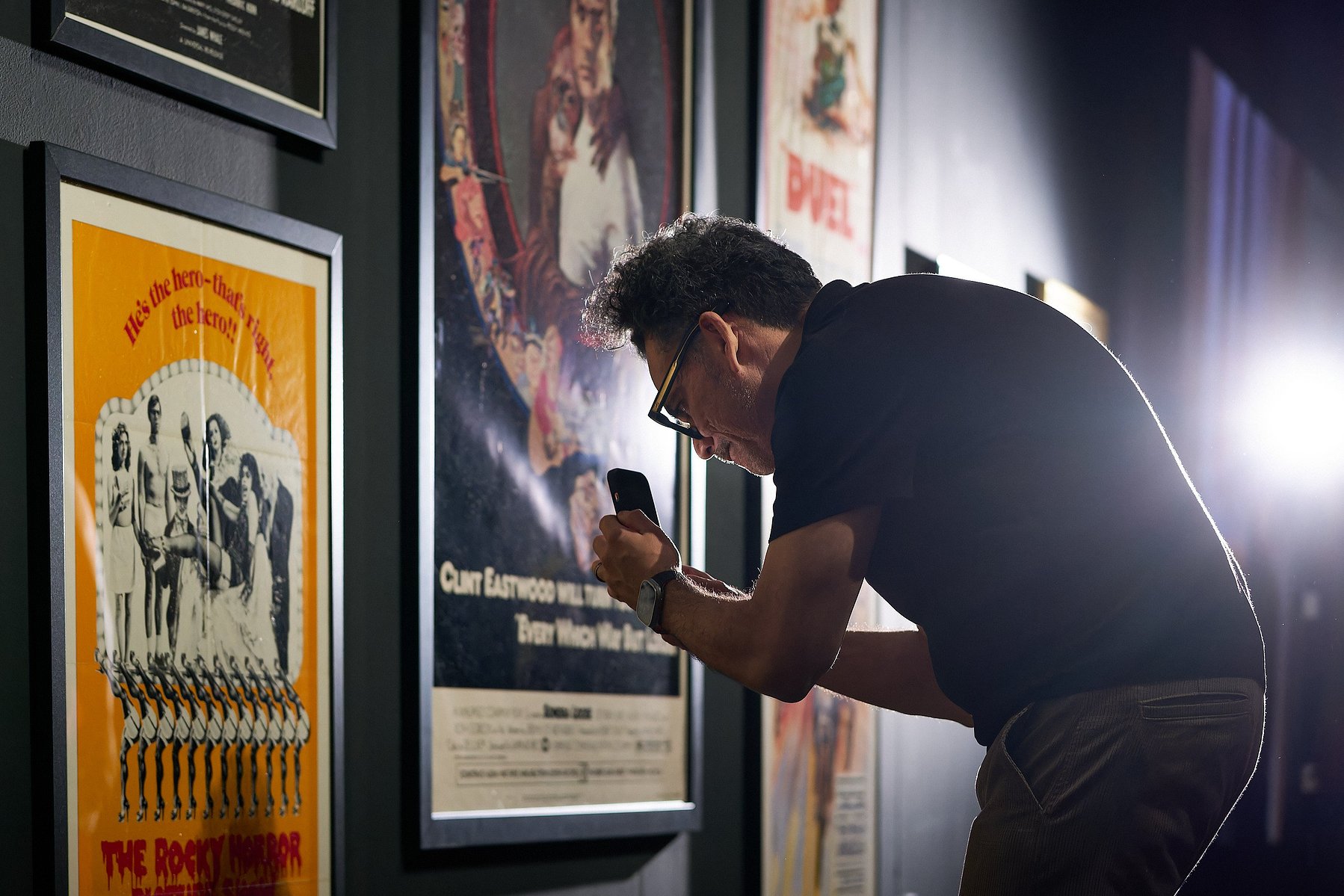 A man is inspecting and photographing art at "Painted for the Pictures" at Muzeo in Anaheim, CA