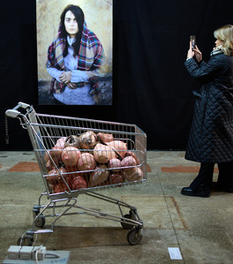 a shopping cart filled with women's breasts and a portrait photograph at an exhibition in Keskturg
